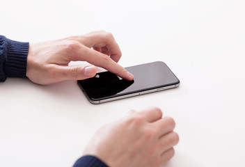Hand using smart mobile phone on wooden table and light blurred background

