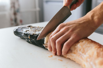 Male cook in the kitchen cut the pike.