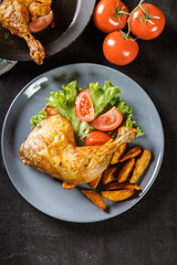 Roasted chicken legs with potato wedges and tomatoes