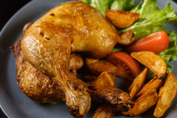 Roasted chicken legs with potato wedges and tomatoes