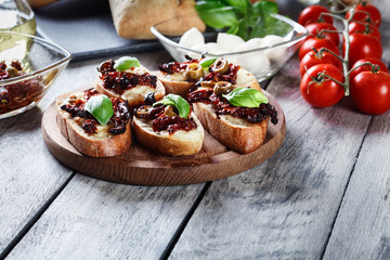 Appetizer bruschetta with sun-dried tomatoes, olives and mozarella.