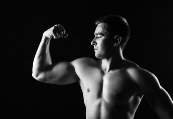 Fototapeta na wymiar Muscular man bodybuilder. Man posing on a black background, shows his muscles. Bodybuilding, posing, black background, muscles - the concept of bodybuilding. Article about bodybuilding. 