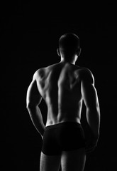 Fototapeta na wymiar Muscular man bodybuilder. Man posing on a black background, shows his muscles. Bodybuilding, posing, black background, muscles - the concept of bodybuilding. Article about bodybuilding. 