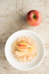 Bowl of Oatmeal and Apple Slices on Wooden Background