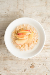 Bowl of Porridge and Apple Slices on Wooden Background