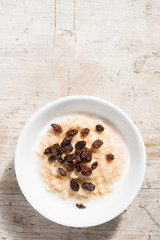 Bowl of Oatmeal and currants on White Wooden Background