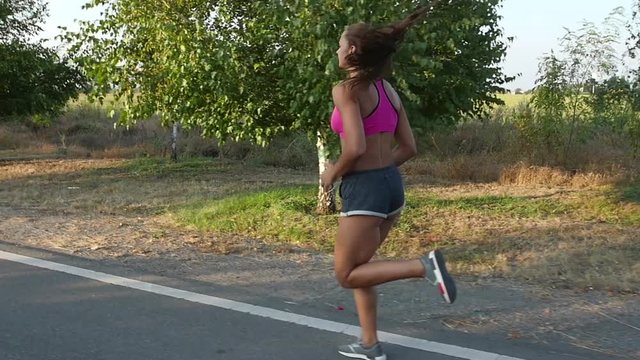 Morning jogging beautiful girl on a country road. Slow motion