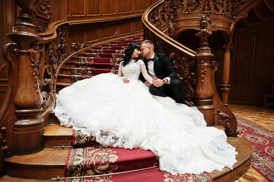 Charming wedding couple sitting on rich wooden stairs on great r