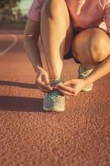 Female athlete tying laces for jogging , sunset ,  vintage
