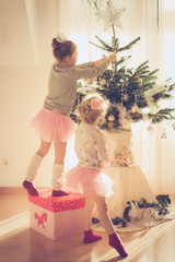 two little sisters decorating christmas tree