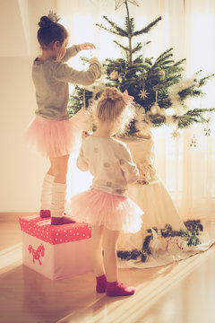 two little sisters decorating christmas tree