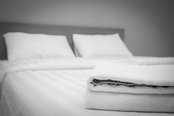  Close up white towels lying on the bed ,  black and white