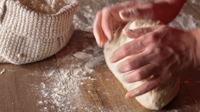 Making bread - woman hands kneading the dough, closeup