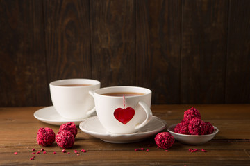 Two cups of hot tea and strawberry chocolate candies
