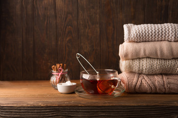 Knitted sweaters and to cup of hot tea, wooden background