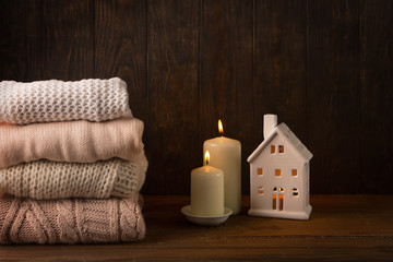 Obraz na płótnie Canvas Cozy and winter background, knitted sweaters and white candles on old rustic wooden board. Christmas holidays time concept, Selective focus