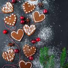 Christmas gingerbread cookies with festive decoration on black stone background, top view
