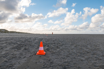 Traffic cone in the sand with man running