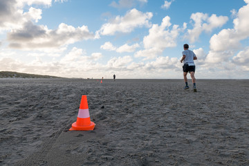Traffic cone in the sand with man running