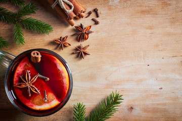 Hot mulled wine with spices on wooden table, from above