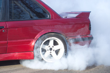 A red  car accelerating with smoke coming from wheels © kajani