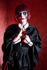 woman with gothic makeup in black cloak with crosses on their hands