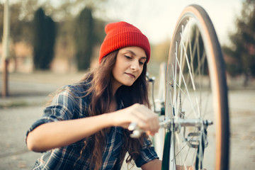 Young hipster girl install bicycle wheel