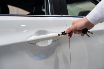 Hand holding car key in door lock