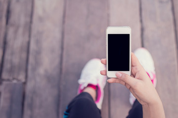 Young woman sitting on old wooden floor with hands holding smart