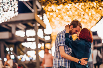 Happy couple embracing in the evening on a light garlands