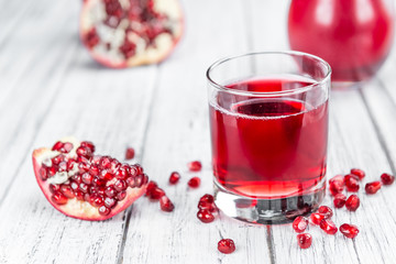 Portion of Pomegranate juice on wooden background (selective foc