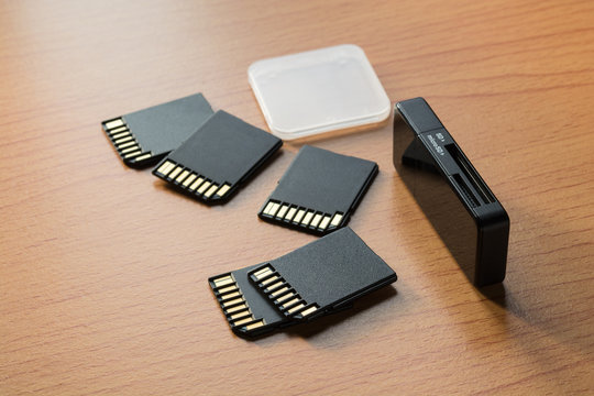 Black memory cards and card reader on wooden background