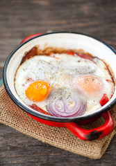 Baked eggs with bacon, red pepper and onion