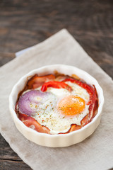 Baked eggs with bacon, red pepper and onion