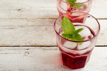 glass with red drink with mint and ice