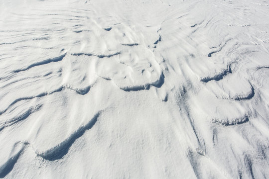 Snow Surface With Small Frozen Snow Waves Drifted By Cold Wind.