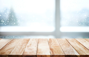 Empty wood table on blur window view with pine tree in snow fall.winter  season  background