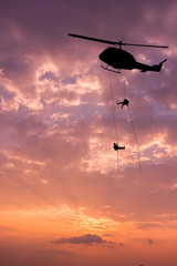Fototapeta na wymiar Silhouette of helicopter, soldiers rescue helicopter operations on sunset sky background.