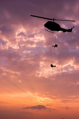 Silhouette of helicopter, soldiers rescue helicopter operations on sunset sky background. © yotrakbutda