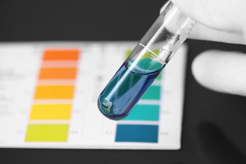 Person wearing gloves testing the PH of a chemical in a test tube