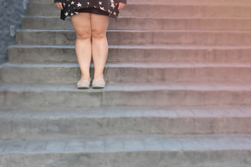 woman legs stand still on stone staircase brown casual shoes and black casual dress in daytime / woman leg walk stairs