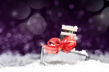 perfume bottle in the snow on a purple background