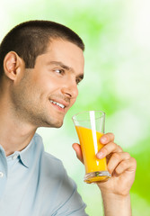 happy smiling man drinking orange juice, outdoors