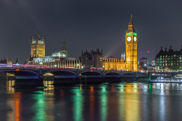 Illuminated Big Ben with bridge and reflection on the river in the foreground at night London United Kingdom. Clock tower.