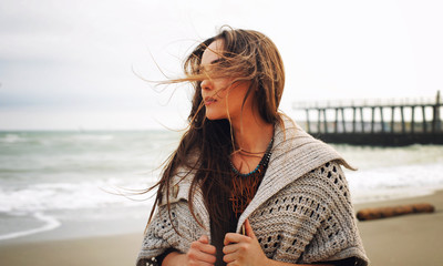 Fashion woman portrait against a pier on a sea beach, autumn outdoor fashion