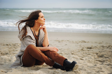 Fototapeta na wymiar Calm beautiful woman sit alone on a beach sand and look at the water