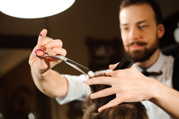 Master cuts hair and beard of men in the barbershop