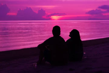 Wall murals Pink Silhouette of the couple enjoying the sunset on the beach