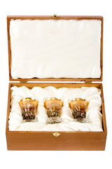 Three vintage shot glasses with gold plating in wooden box on white background