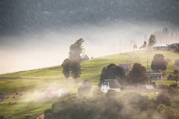 Alpine village in mountains. Smoke, bonfire and haze over hills